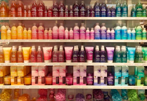 A vibrant display of colorful moisturizer bottles arranged on a wooden shelf.