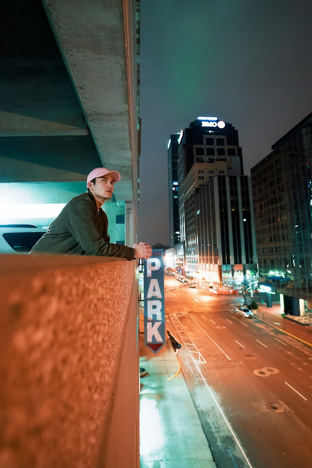 man leaning on concrete railing on building