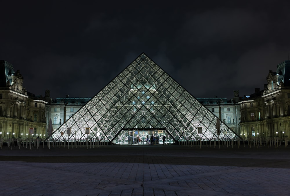 bâtiment en verre transparent en forme de pyramide pendant la nuit