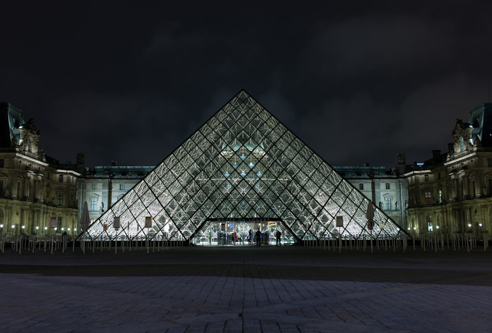 edifício de vidro transparente em forma de pirâmide durante a noite