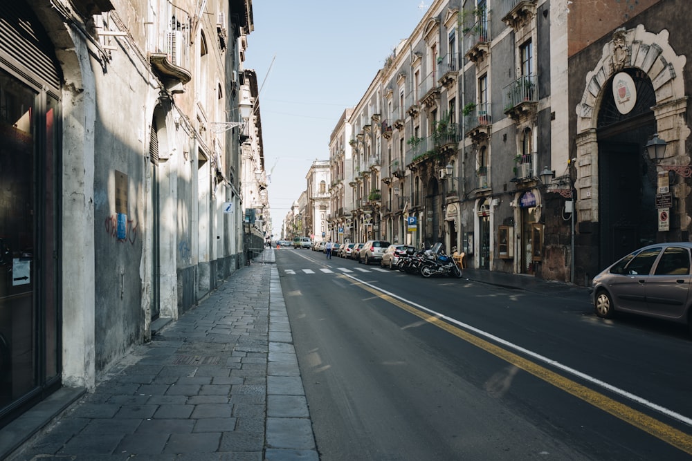 cars parked on side of the road in between buildings during daytime