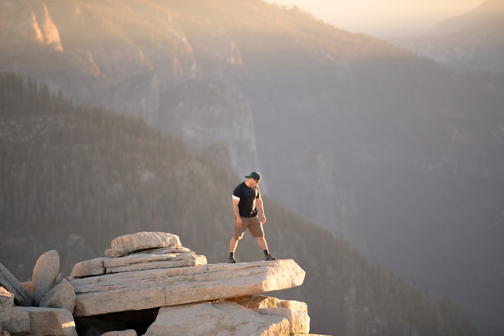 man standing on rock cliff near mountain