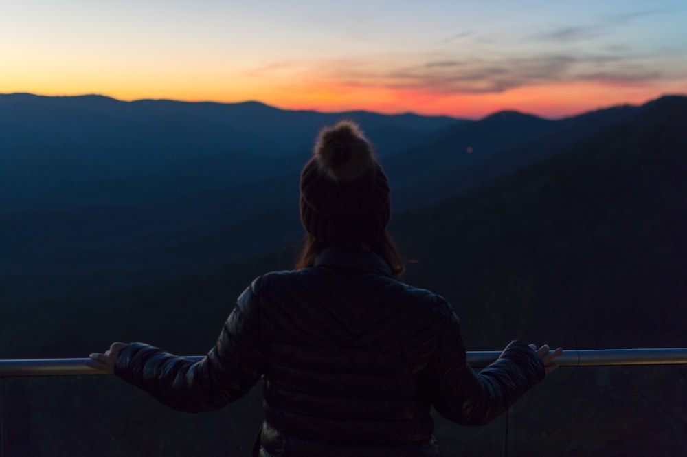 Donna in piedi sul tetto mentre tiene sulla recinzione che guarda le montagne