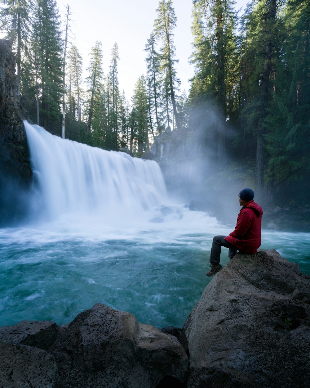 man sitting near waterfalls