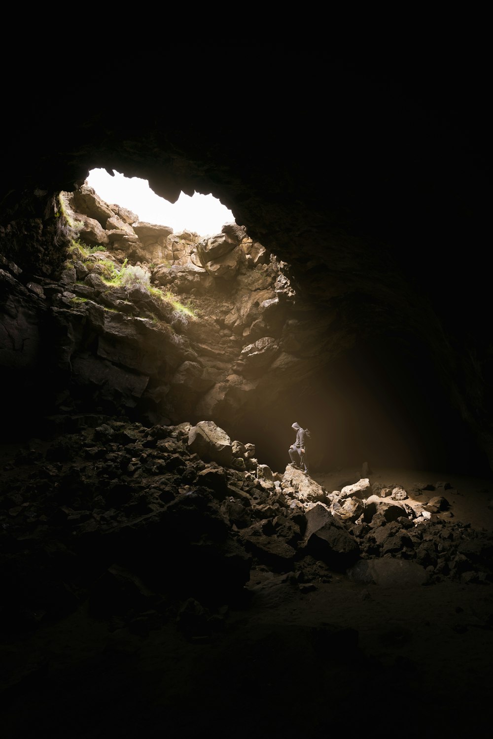 a person standing in a cave with a light coming through