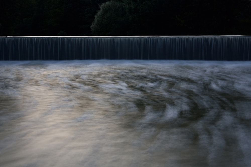 um grande corpo de água com uma cachoeira ao fundo