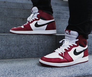 person wearing pair of red-and-white Air Jordan 1 shoes