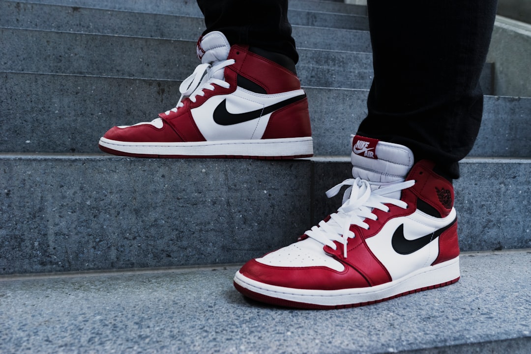 person wearing pair of red-and-white Air Jordan 1 shoes