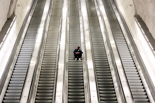 man sitting on escalator