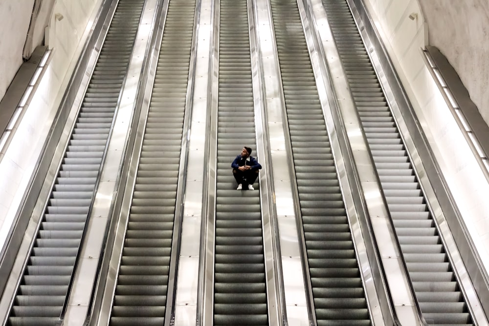 Mann sitzt auf Rolltreppe