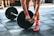 Close-up of a woman adjusting weights on a sturdy barbell in a fitness studio.