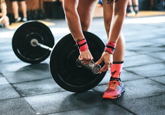 person locking gym plates on barbell