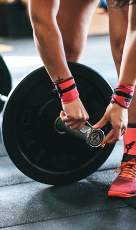 person locking gym plates on barbell