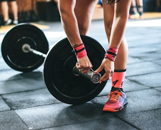 person locking gym plates on barbell