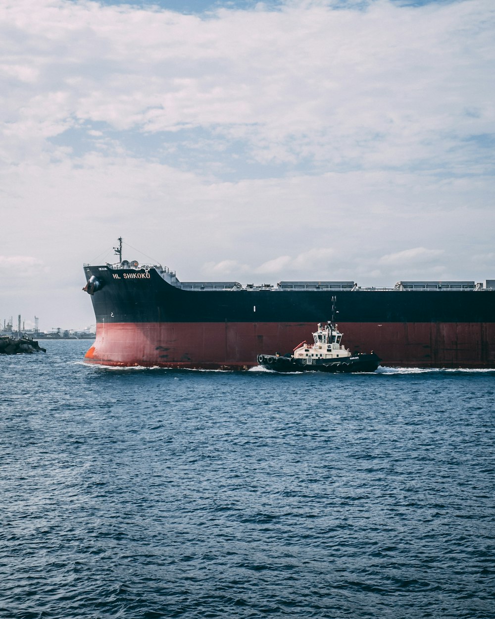 navio preto e vermelho ao lado de navio menor preto e branco