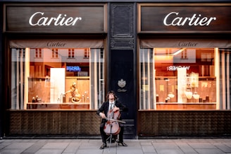 man playing cello in front of store