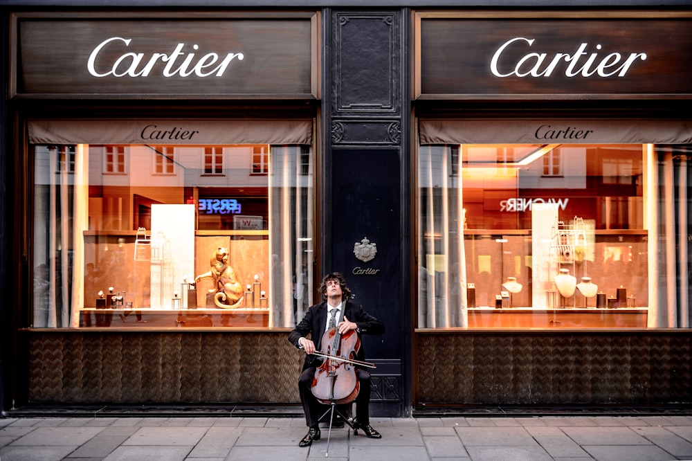 uomo che suona il violoncello davanti al negozio