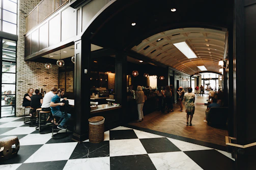 Bright, airy cafe scene with customers enjoying coffee and pastries near large windows.