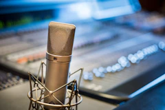A studio microphone in front of an audio mixing console