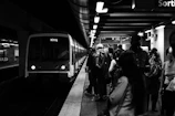 group of people waiting for the train in grayscale photography