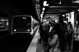 group of people waiting for the train in grayscale photography