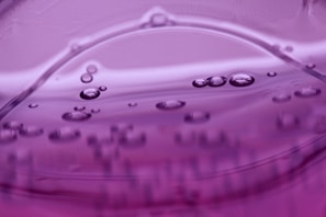 Purple liquid with visible air bubbles suspended in it, creating a smooth, wavy surface effect.