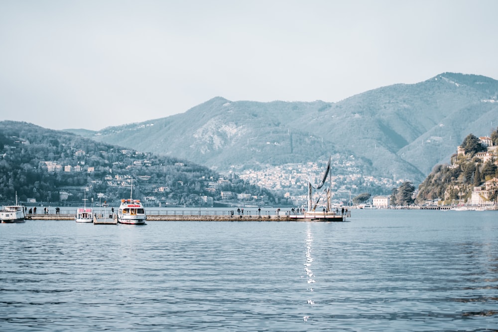 yacht docking beside wooden dock with mountain in distance