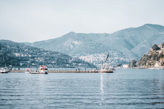 yacht docking beside wooden dock with mountain in distance in Temple de Volta Italy