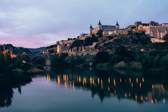 A cozy hotel balcony overlooking a historic cityscape at twilight, lights beginning to twinkle.