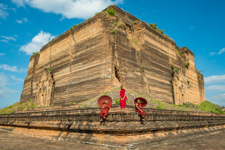 Volunteers laying bricks with devotion at the temple construction site under a bright sky.
