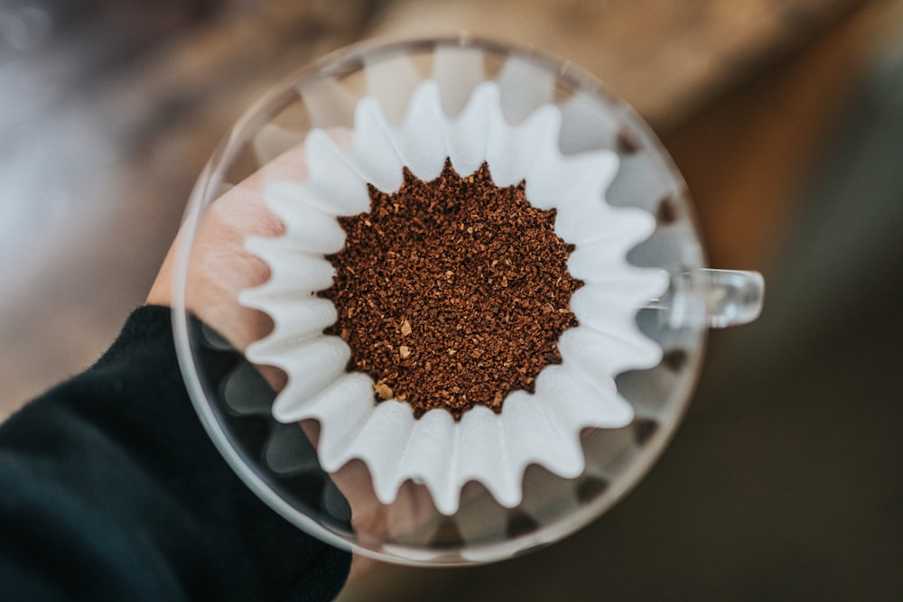 Persona sosteniendo una taza de vidrio transparente