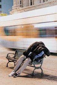 person sleeping on black steel bench