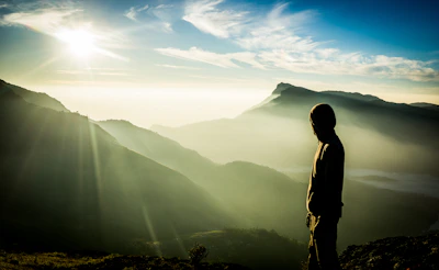 Ecuadorian athlete meditating at dawn on a volcanic mountain ridge with mist and soft orange light.