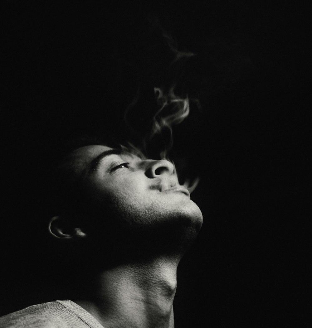 Photographie en niveaux de gris d’un homme fumant