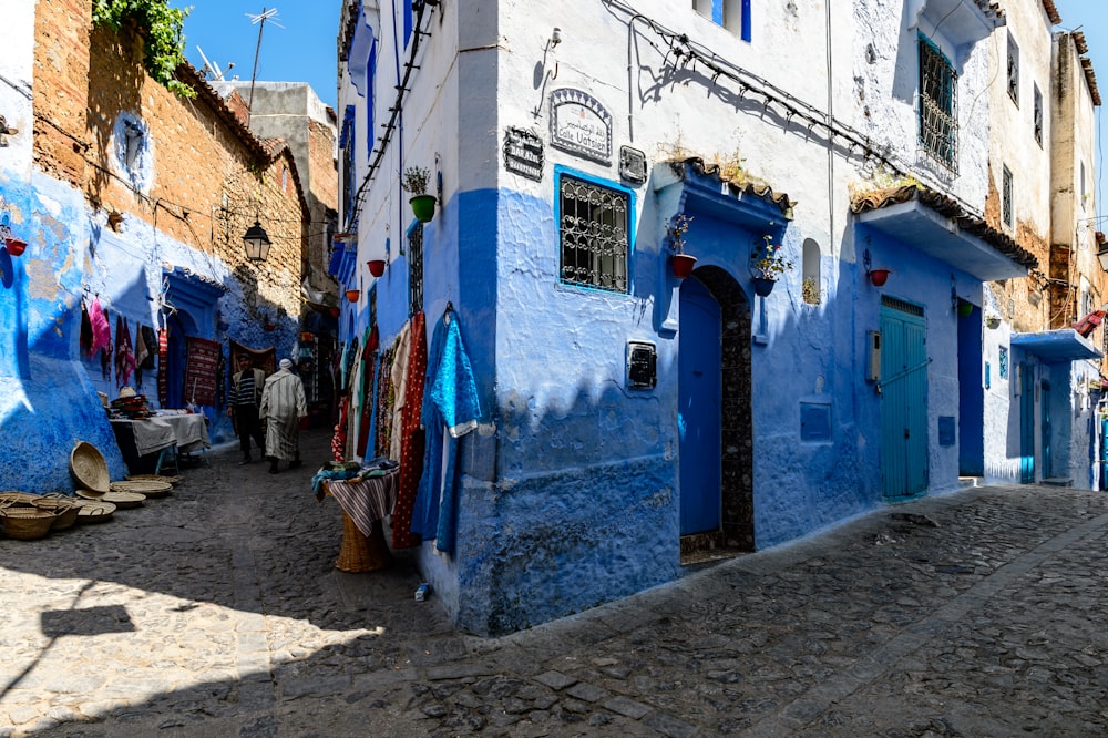 two person walking in between blue and white concrete building