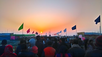 A passionate crowd waving flags at a political rally during sunset.