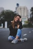 woman smiling while sitting on road with hand resting on top of her knee