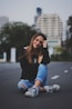 woman smiling while sitting on road with hand resting on top of her knee