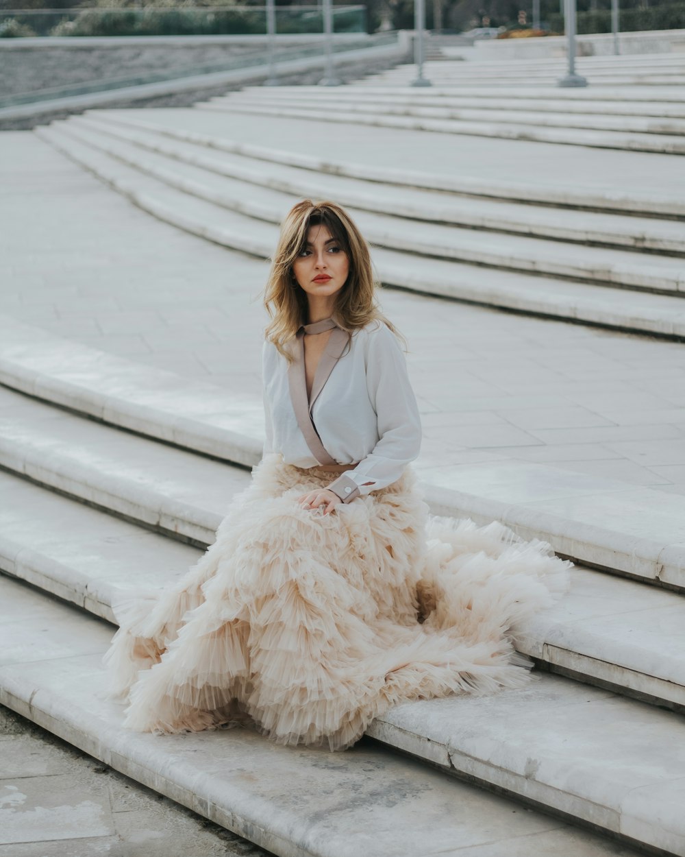 brown haired woman in white dress sitting on gray concrete stair during day time