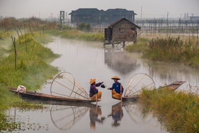 two men riding boats on water myanmar google meet background