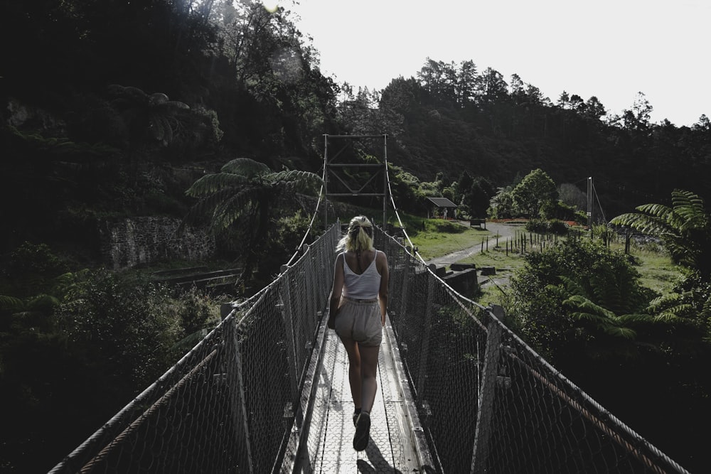 woman in white tank top waling in bridge during daytime