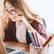 woman biting pencil while sitting on chair in front of computer during daytime