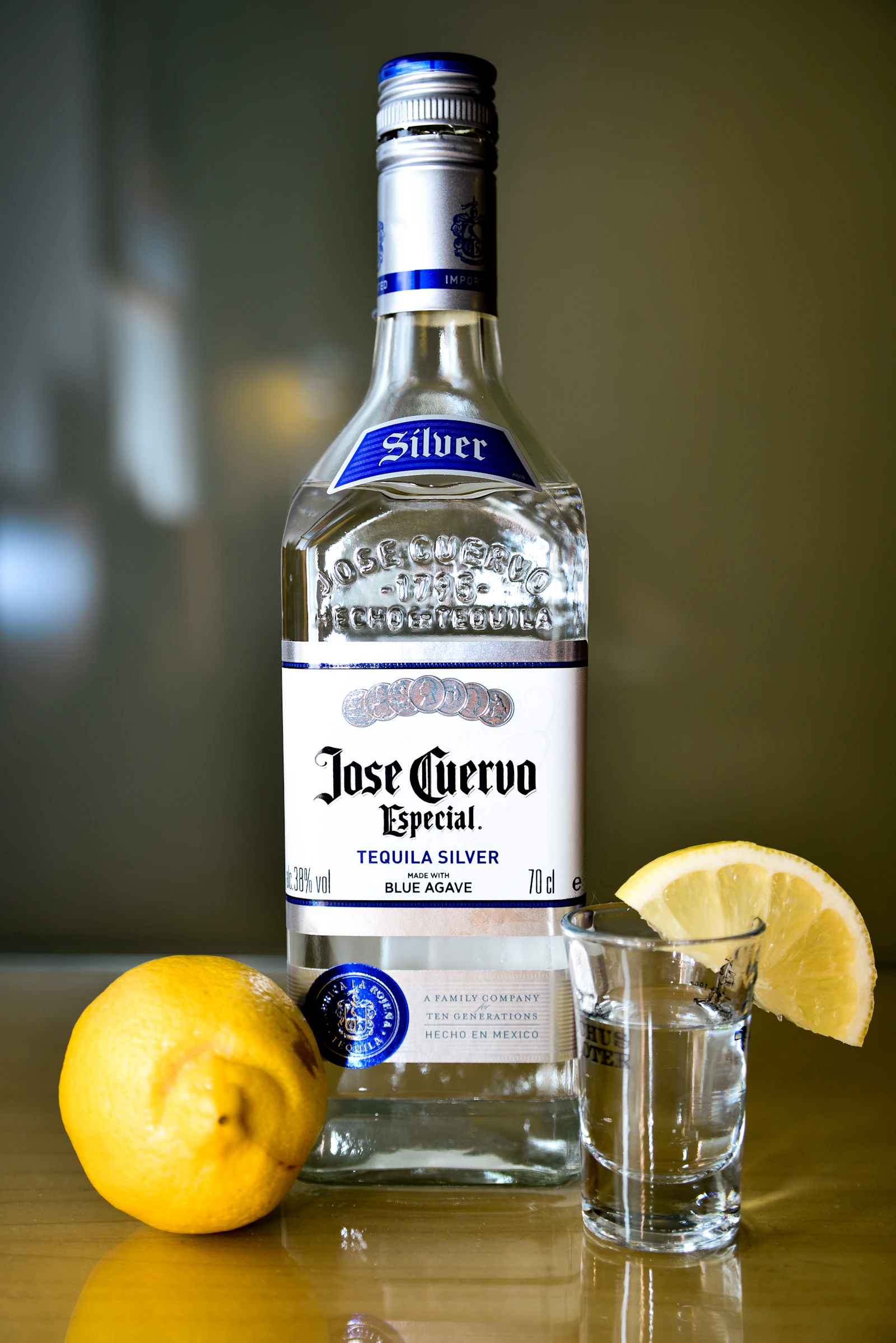 Botella de tequila blanco con un caballito y limón