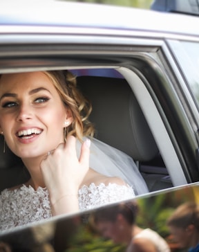 woman wearing wedding dress smiling inside car