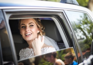 woman wearing wedding dress smiling inside car