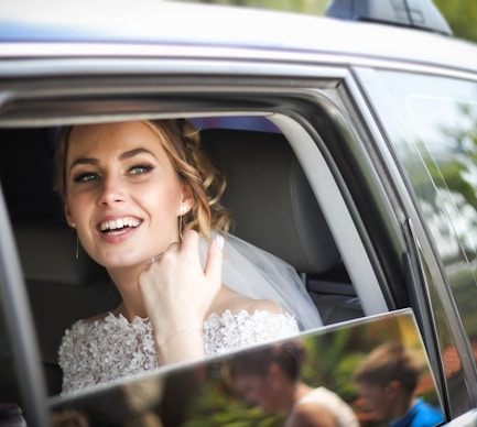 woman wearing wedding dress smiling inside car