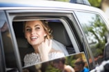 woman wearing wedding dress smiling inside car