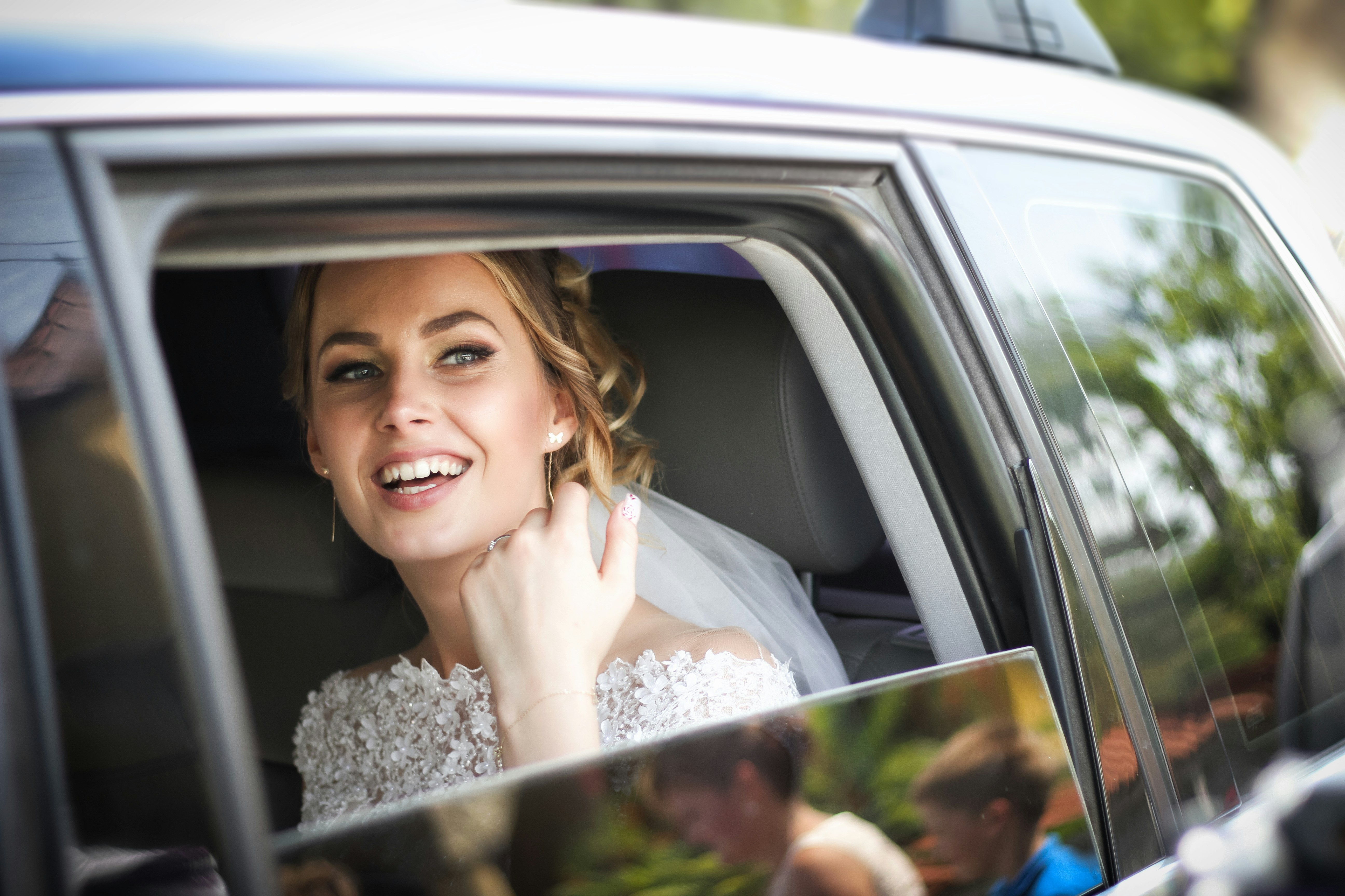 Bride in the car looking outside and smiling.