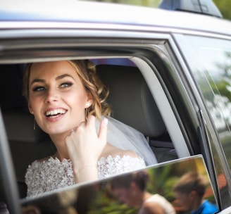woman wearing wedding dress smiling inside car