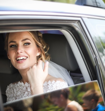 woman wearing wedding dress smiling inside car